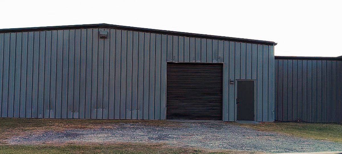Commercial metal building after washing and repainting dark gray with a black roll door